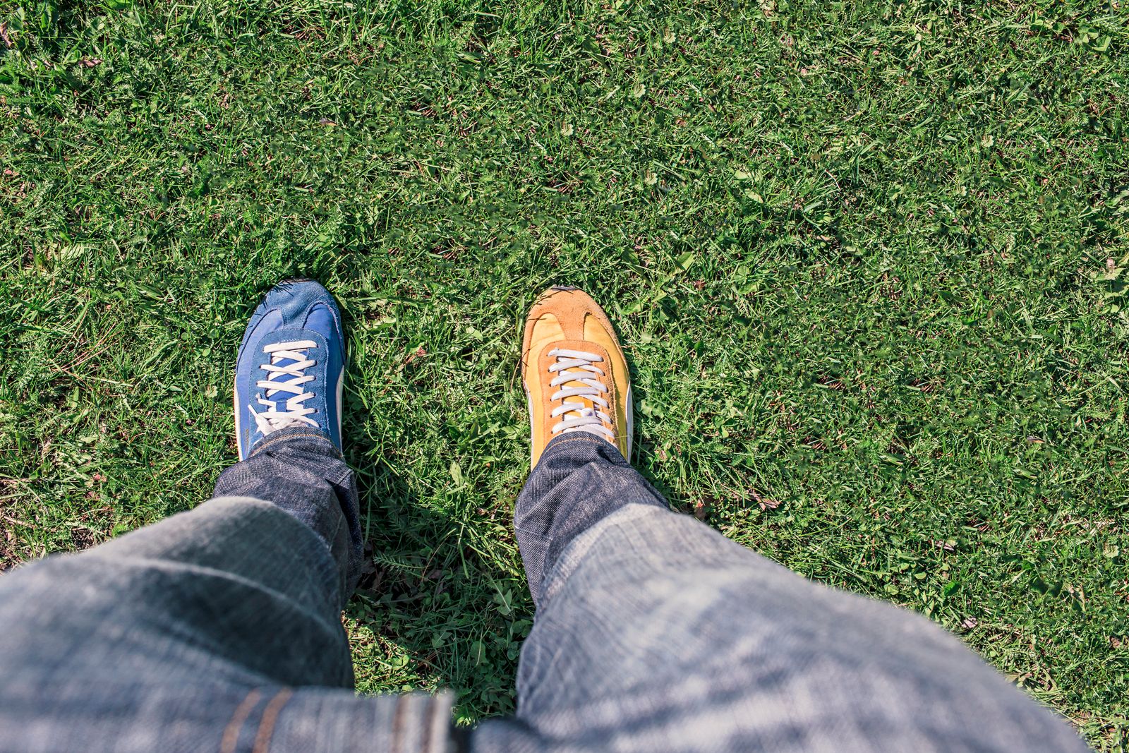 Une personne portant des chaussures assorties se tient sur de l'herbe verte, mettant en avant les différences et l'indiv